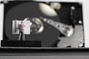 concepto de big data: ingeniero en miniatura que trabaja con una mesa de dibujo con fondo de disco duro abierto foto