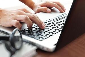 Cerca de la mano del hombre de negocios trabajando en la computadora portátil de pantalla en blanco en el escritorio de madera como concepto foto