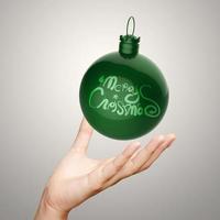 mano mostrando feliz navidad en bola de adorno foto