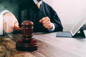 justice and law concept.Male judge in a courtroom striking the gavel,working with digital tablet computer docking keyboard on wood table,filter effect photo