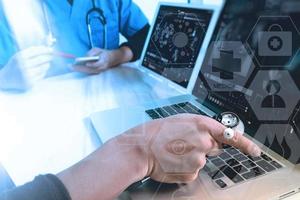 medical doctor hand working with smart phone,digital tablet computer,stethoscope eyeglass,on wooden desk,virtual graphic interface icons screen photo