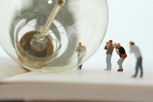 Creative idea concept - miniature photographer with vintage light bulb on open paper notebook photo