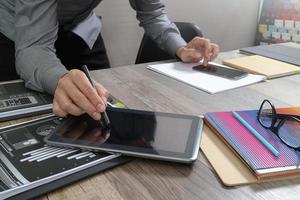 Website designer holding smart phone and working computer digital tablet on wood table photo