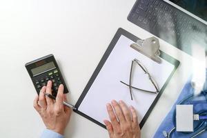 vista superior del concepto de costos y tarifas de atención médica. La mano de un médico inteligente usó una calculadora para costos médicos en un hospital moderno foto