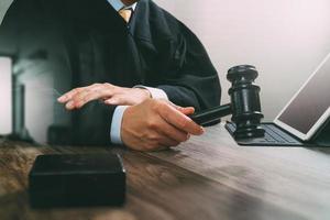 justice and law concept.Male judge in a courtroom with the gavel,working with digital tablet computer docking keyboard on wood table,filter effect photo