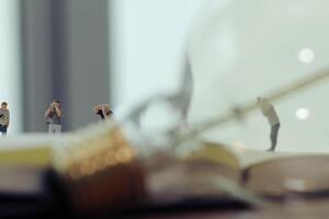 Creative idea concept - miniature photographer with vintage light bulb on open paper notebook photo