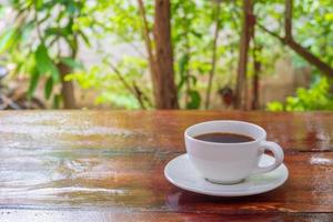 A cup of coffee on a wooden table in the morning with the late morning sunlight.A cup of coffee on a wooden table in the morning with the late morning sunlight. photo