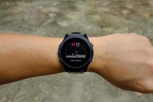 Heart rate status on modern round-faced GPS multisport digital smartwatch on left hand wrist, selective focus photo