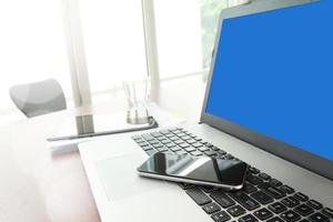 Office workplace with laptop computer and smart phone and stylus with digital tablet  on wood table photo