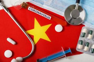 Coronavirus, nCoV concept. Top view of a protective breathing mask, stethoscope, syringe, pills on the flag of Vietnam. photo