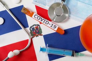 Coronavirus, the concept COVid-19. Top view of a protective breathing mask, stethoscope, syringe, pills on the flag of the Dominicana. photo