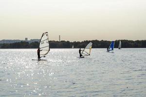 tablista. el hombre está navegando en el fondo de los rascacielos. hombre en una tabla de windsurf. windsurf en la ciudad. Deportes acuáticos. surfeando con una vela. equipo de windsurf. Estilo de vida activo. foto