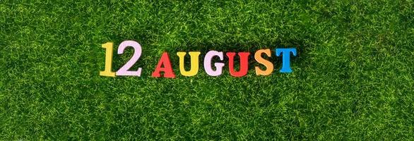 August 12. Image of wooden colored letters and numbers on August 12 against the background of a green lawn. photo