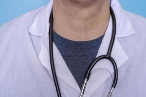 primer plano de un médico varón con un abrigo médico blanco y un estetoscopio con una camiseta. foto