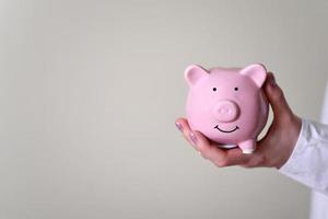 The hand holds a piggy bank in the form of a pig. photo