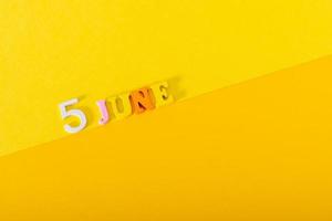 June 5, World Environment Day. Wooden letters and numbers on a yellow background. photo
