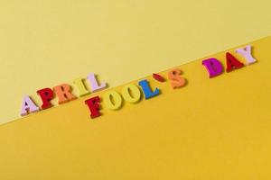 Wooden letters the first of April on a yellow background. The concept of the holiday, photo