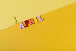 Wooden letters the first of April on a yellow background. The concept of the holiday, photo