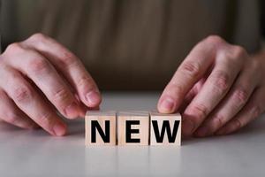 Businessman holding wooden cubes with new word. photo