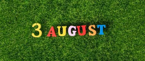 August 3. Image of wooden colored letters and numbers on August 3 on the background of a green lawn. A summer day. photo