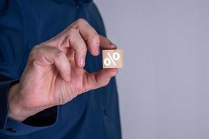 el hombre de negocios muestra un cubo de madera con un símbolo de porcentaje o porcentaje. foto