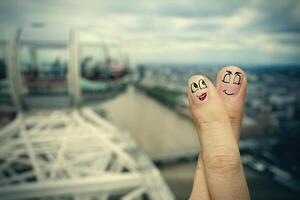 the happy finger couple in love with painted smiley on london city blurred background photo