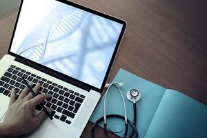 top view of Medicine doctor hand working with modern computer and dna layer effect on wooden desk as medical concept photo