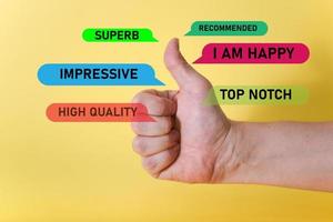 A hand showing a thumbs-up sign on a yellow background. photo