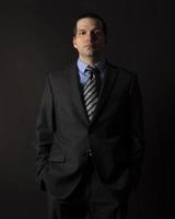 A man in a black suit on a black background. photo