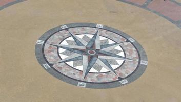 A drawn compass on a tile with the cardinal directions. photo