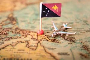 la bandera de papúa nueva guinea y el avión en el mapa mundial. foto