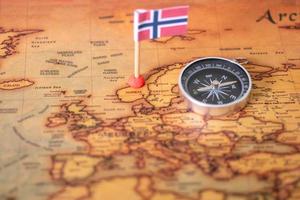 Norwegian flag and compass on the world map. photo