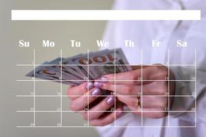 dinero en manos de una mujer y un calendario. foto