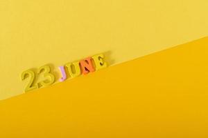 Wooden calendar on yellow background, top view, date 23 June photo