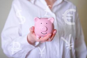 The girl holds a pink piggy bank in her hand. photo