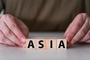 A businessman holds wooden cubes with the word Asia. photo