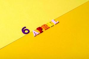 Wooden letters of the sixth of April on a yellow background. photo