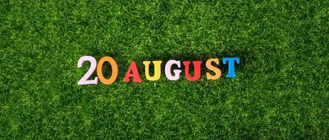 August 20. Image of wooden colored letters and numbers on August 20 against the background of a green lawn. photo