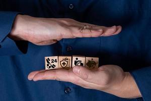 The hand holds wooden cubes with insurance icons. photo