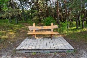 Wooden bench made of logs and placed in the forest photo