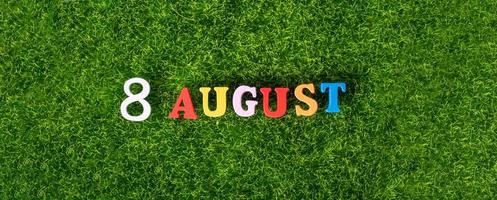 August 8. Image of wooden colored letters and numbers on August 8 against the background of a green lawn, World Cat Day. A summer day. photo