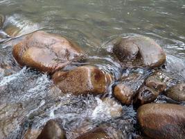 agua que fluye sobre rocas rocosas lavadas por el fluido del río increíble cascada de agua sobre rocas naturales foto