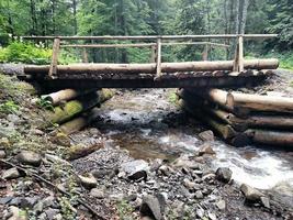 río de montaña que fluye bajo el puente de madera foto