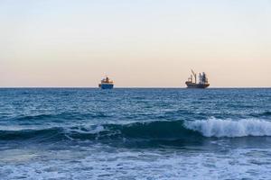 Cargo ships on the horizon of the Mediterranean sea. photo