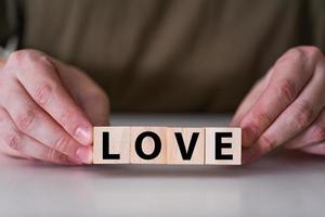 A businessman holds wooden cubes with the word Love. photo