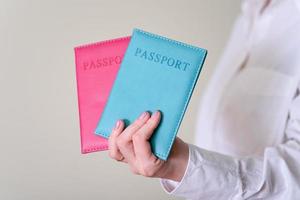 A woman's hand holding two passports on a gray background. photo