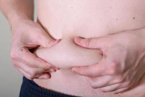 Hand's man touching his fat belly skin. photo