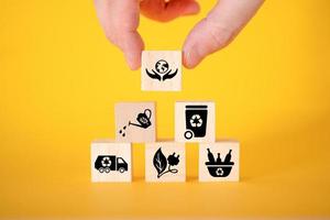 Ecology concept with icons on wooden cubes, yellow background. photo