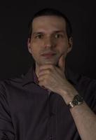 A man in a crimson shirt on a black background. photo