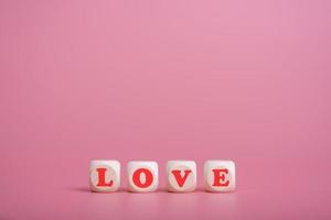 Text wooden blocks spelling the word love on pink background photo